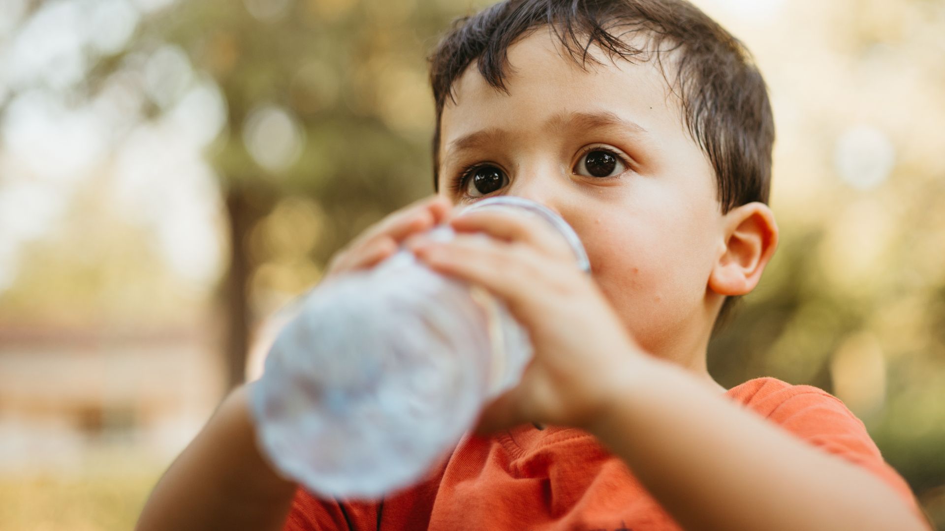 Dziecko pijące wodę butelkowaną w której znajduje się mikroplastik Dziecko pijące wodę butelkowaną w której znajduje się mikroplastik
