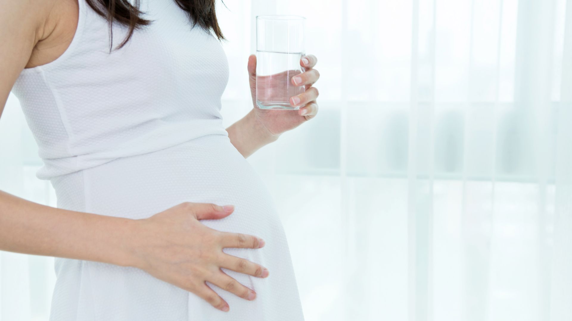 Ciężarna kobieta trzymająca szklankę z wodą Ciężarna kobieta trzymająca szklankę z wodą