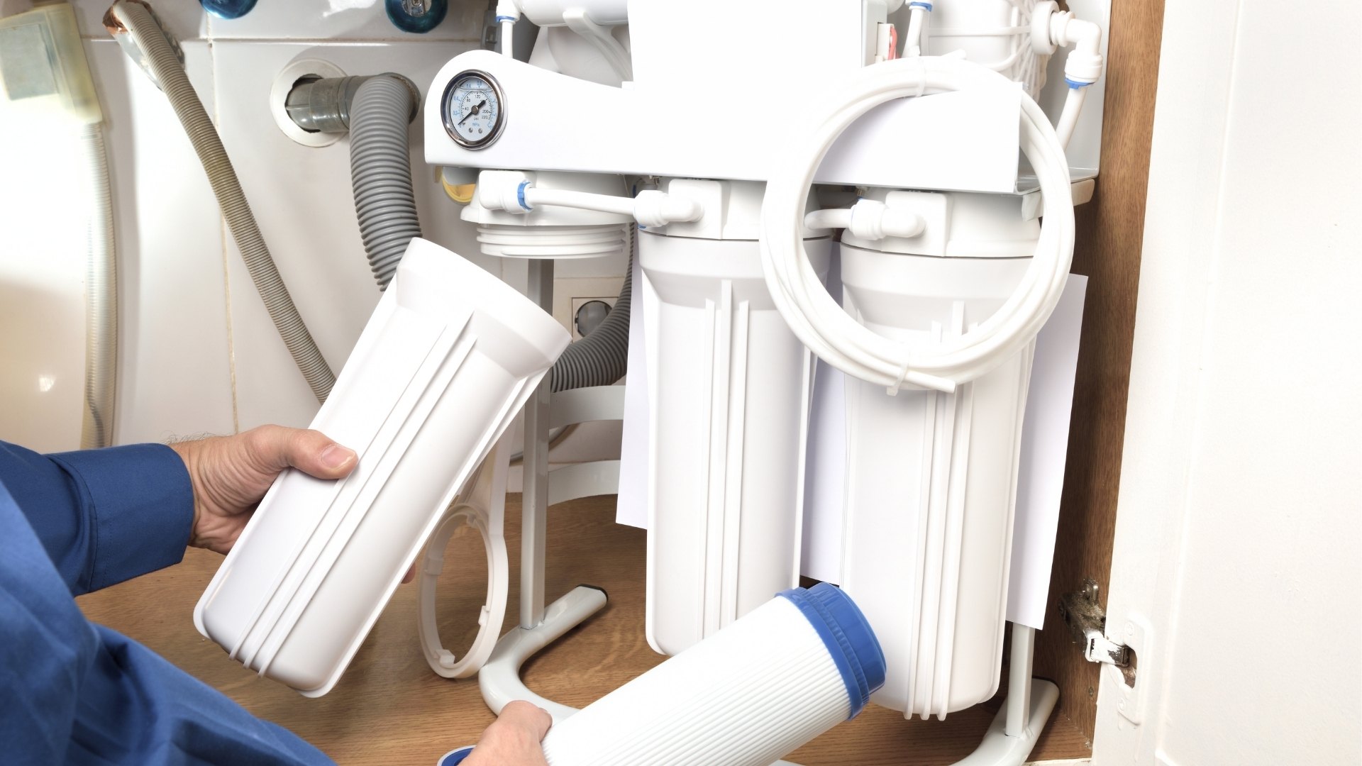 Mężczyzna wymieniający filtr węglowy w filtrze odwróconej osmozy Mężczyzna wymieniający filtr węglowy w filtrze odwróconej osmozy